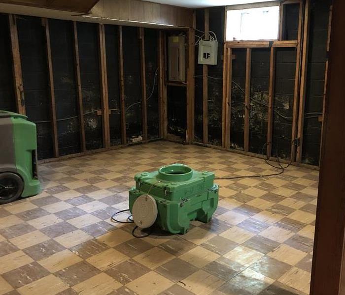 Basement with water from storm damage, walls are to the studs, and SERVPRO machine.