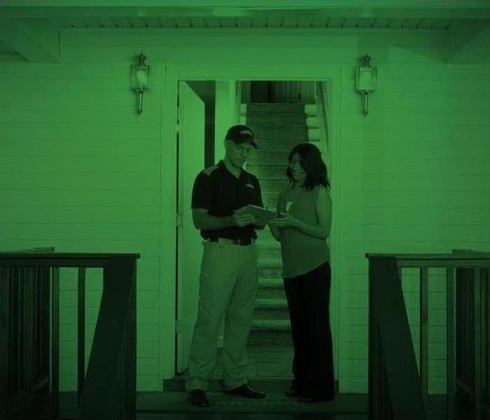 SERVPRO Technician and Homeowner looking at paperwork in front of a home.