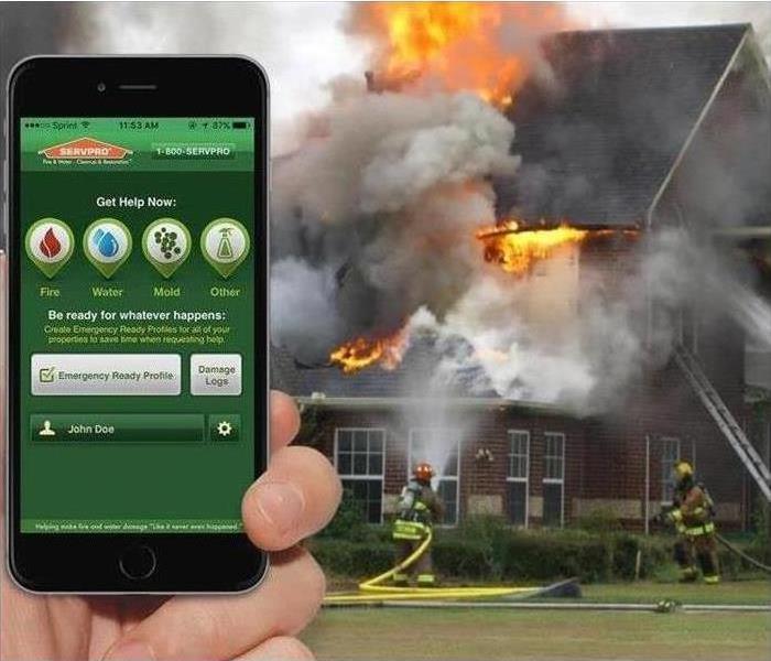Phone with SERVPRO APP and house in the background on fire.