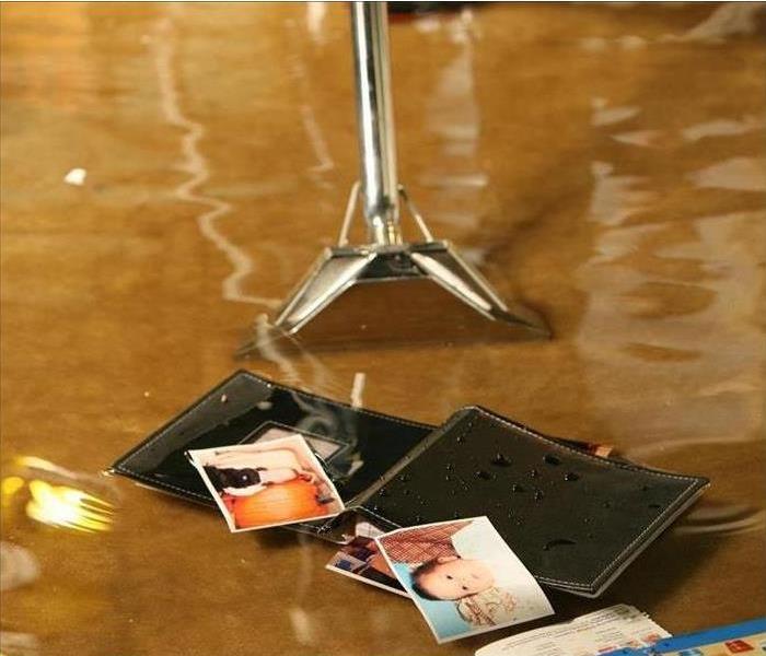 Flood water inside home with extraction tool and wallet with family pictures floating.