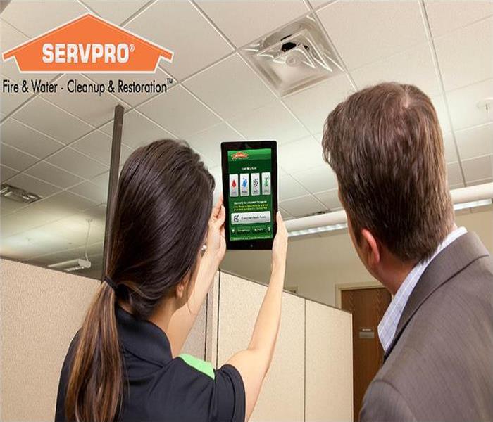 SERVPRO technician holding an iPad with the SERVPRO APP showing a business man.